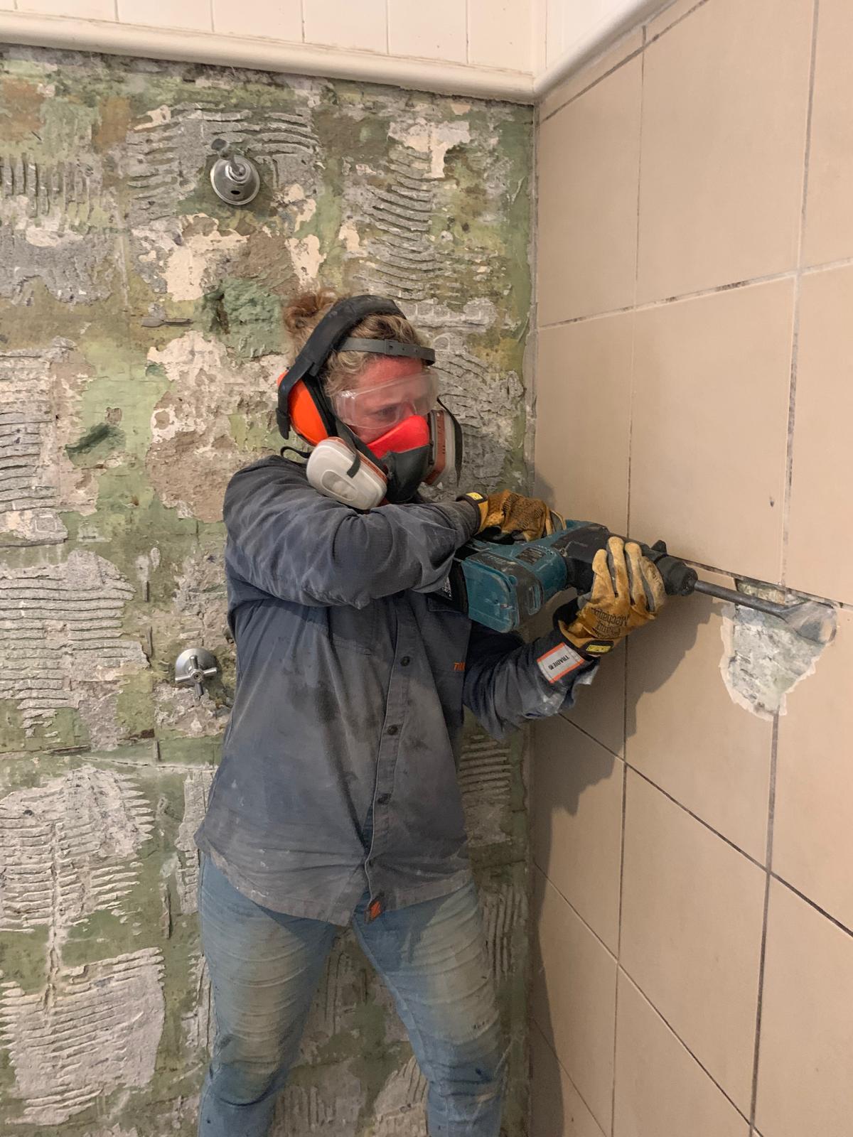 Stacey removing tiles during a bathroom renovation